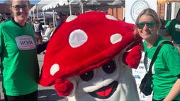 Volunteers Mrs. Carter and Mrs. DelDotto posing with a Mushroom Cap mascot to lift runners’ spirits.